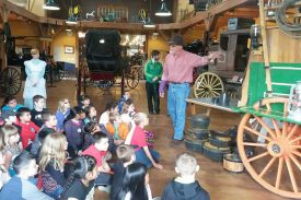 A group of school kids listening to the curator talk about an 1890s chuckwagon and life out on the range
